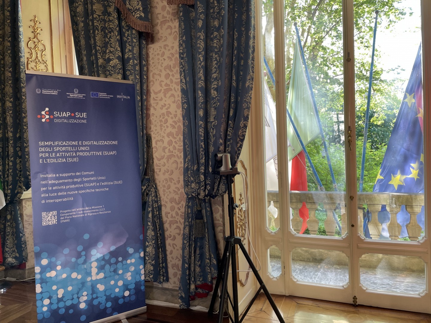 Interno di una sala con rappresentazione di bandiere italiane e dell'Unione Europea
